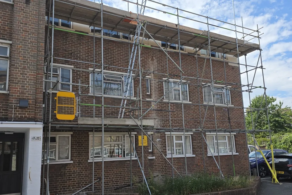 Scaffolding erected across the front of a three-storey block of flats